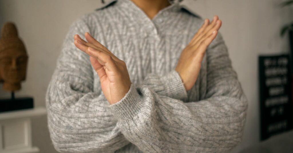 Close-up of a woman crossing her arms in a gesture of refusal, taken indoors.